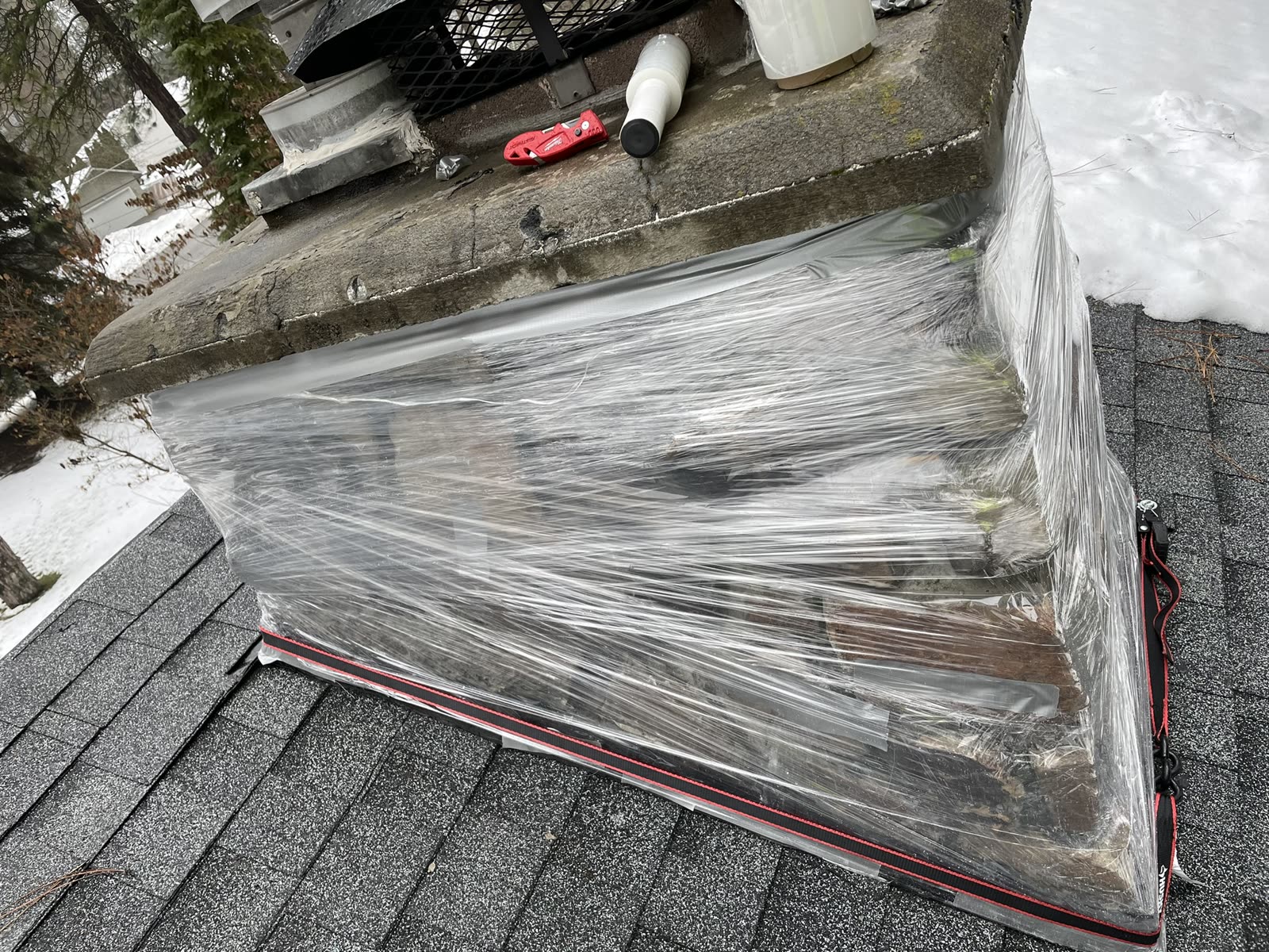 Chimney wrapped and roof area protected while flashing work is underway